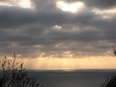 [Sun rays leaking through the dark cloud cover to light portions of the water.]